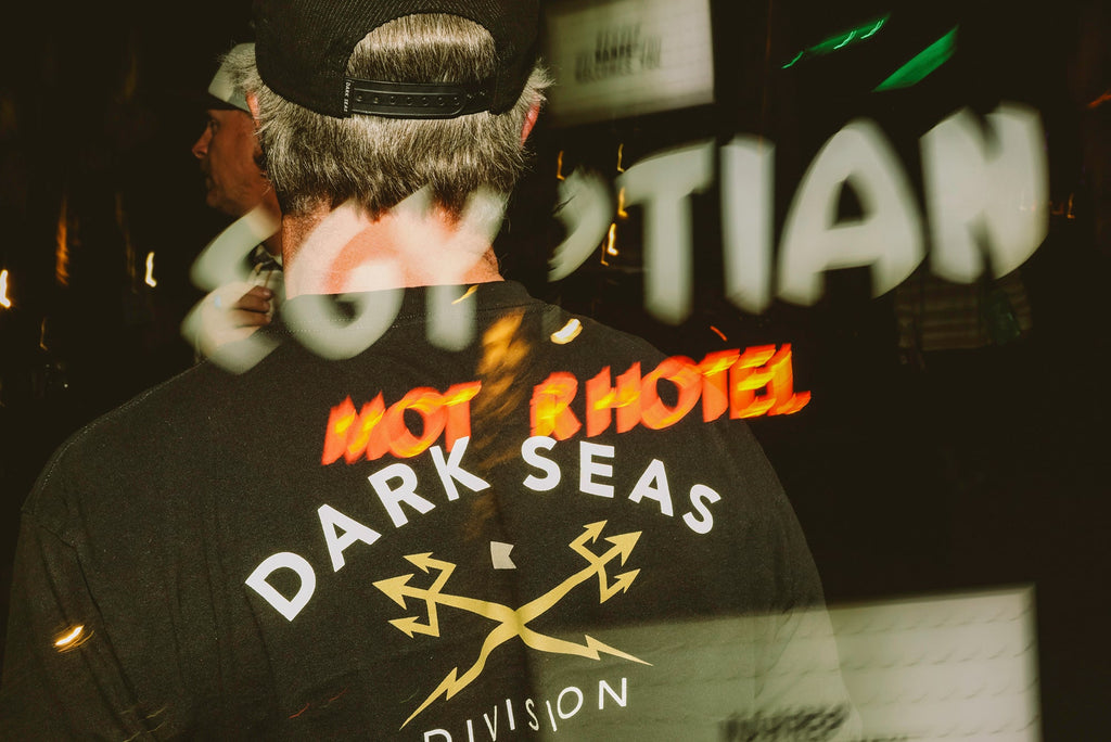 Man in a Dark Seas Headmaster tee with a motel sign reflection overlaid